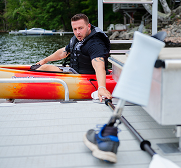 guy grabbing paddle off of dock