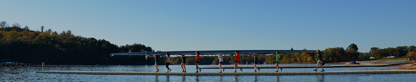 A group of people carry a large canoe down a dock