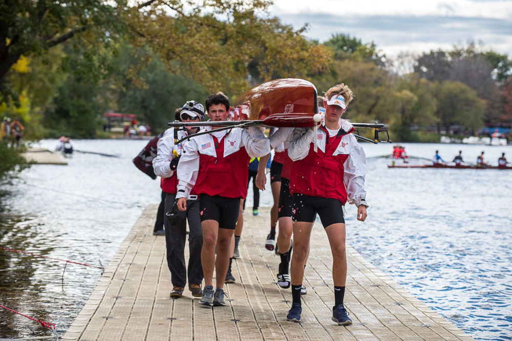 A male rowing team carries their boat