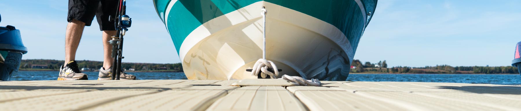 Bottom of teal boat attached by rope to dock