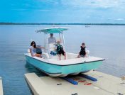 A family with two young boys on a teal boat launches from the dock