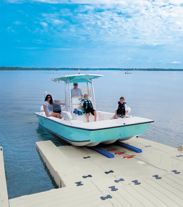 A family with two young boys on a teal boat launches from the dock