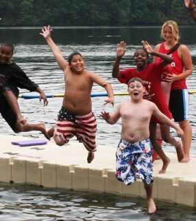 Kids jumping into water off of floating swim platform