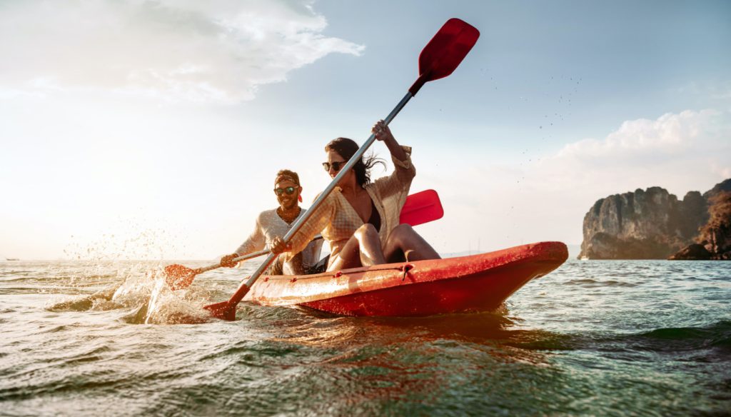 Couple kayaking beside rocky coast line