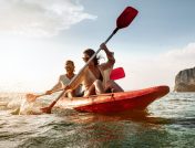 Couple kayaking beside rocky coast line