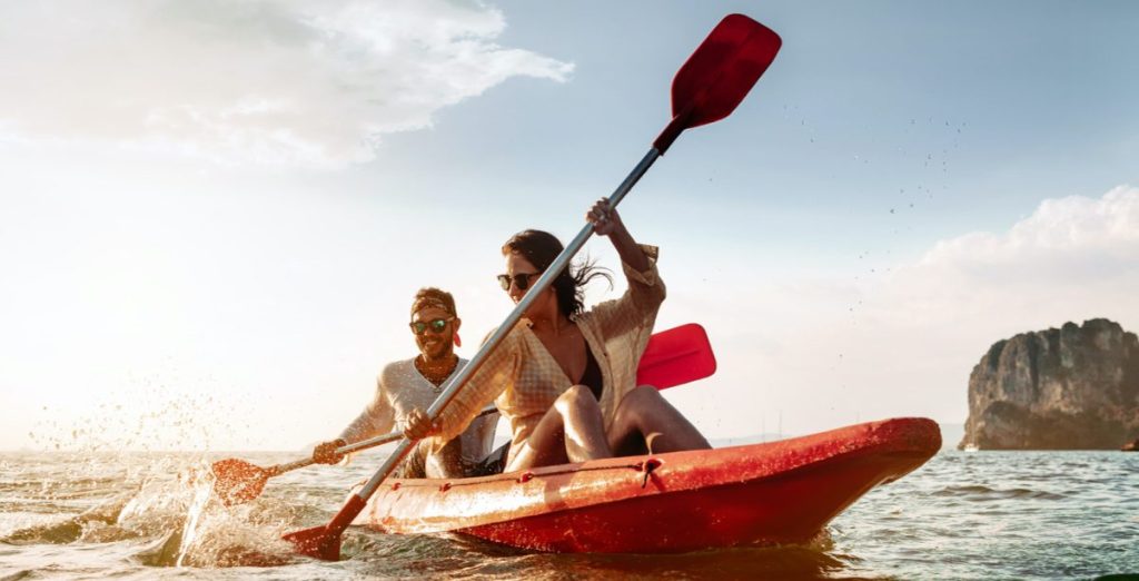 A young couple kayaking in a red boat