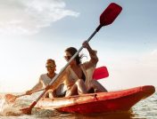 A young couple kayaking in a red boat