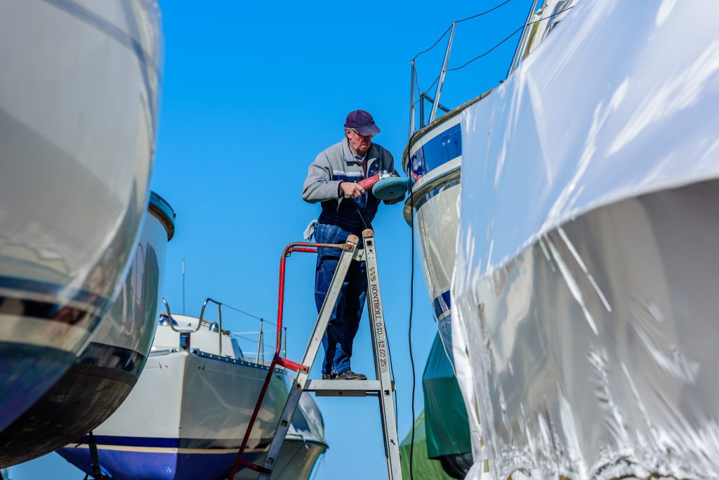 Man sanding boat on ladder