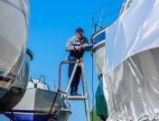 Man sanding boat on ladder