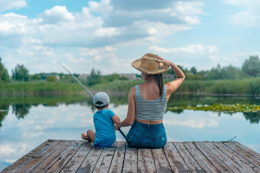 Mom and son sitting on wooden dock while fishing