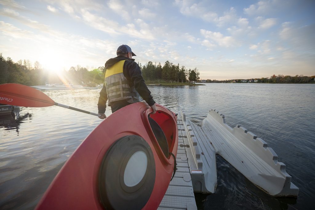 Guy carrying kayak to launch area