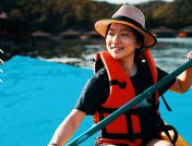 A young female enjoys her kayak while wearing a life vest