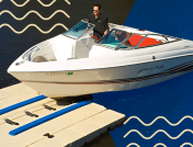 Man driving a white boat onto a mooring dock at a lake in Indiana