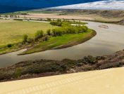 Wide view of a slow moving riverbend banked by trees and fields in North Dakota