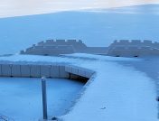 White dock for jet skis covered in snow and surrounded by ice during winter