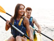 A young couple sharing a yellow kayak and paddling in unison on a lake in North Dakota